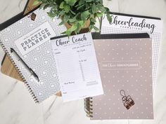 three notebooks and a potted plant on top of a white marble countertop