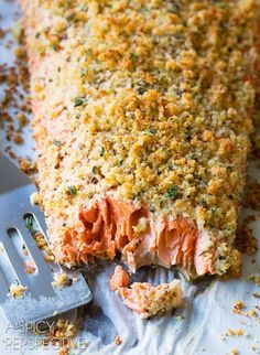 a piece of salmon covered in parmesan and seasoning next to a fork