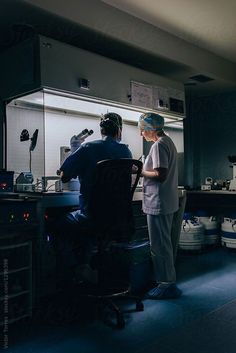 two men in scrubs are preparing food in a kitchen by an open refrigerator door