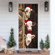 two cows wearing santa hats are standing in front of a door with christmas decorations on it