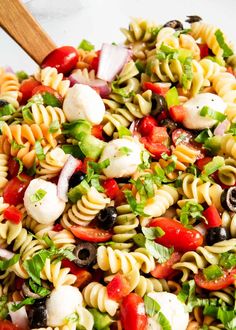 a pasta salad with tomatoes, olives, onions and mozzarella