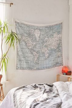 a large map hanging on the wall above a bed in a room with white walls