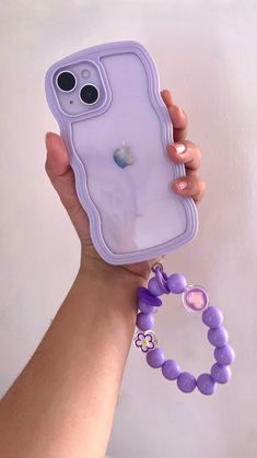 a hand holding a purple cell phone case with a beaded bracelet attached to it