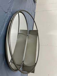 a round mirror mounted to the side of a wall next to a blue painted wall