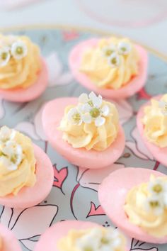 small pink and yellow desserts with white flowers on them sitting on a blue plate