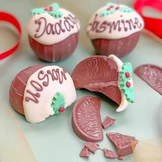 three pieces of chocolate with white frosting and red ribbon around them on a table