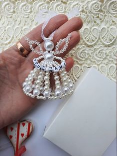 a hand holding a white beaded christmas ornament