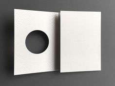 an open book with a circular hole in the middle on a gray surface, showing pages that appear to be folded