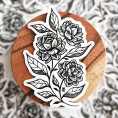 a sticker with flowers on it sitting on top of a wooden surface next to a black and white wallpaper