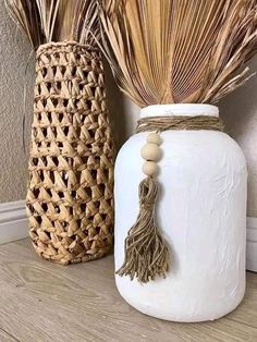 two vases sitting on top of a wooden floor next to each other, one with a tassel hanging from it's side