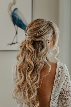 the back of a woman's head with long blonde hair styled into a half - updo