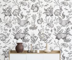 a wallpaper with rabbits and flowers on it in black and white, is next to a cabinet