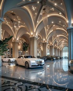 several luxury cars are parked in a large room with high ceilings and chandeliers