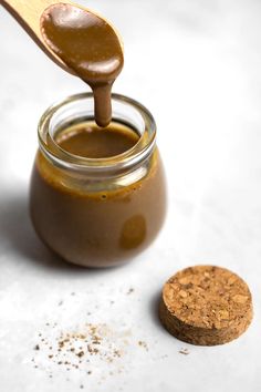 a spoon full of peanut butter next to a jar