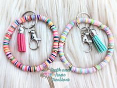 two pairs of colorful bracelets are on a white furnishing with scissors in the middle