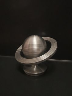 a metal object sitting on top of a black table next to a white and gray wall