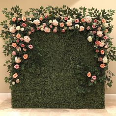 an artificial wall with pink and white flowers on it's sides, surrounded by greenery