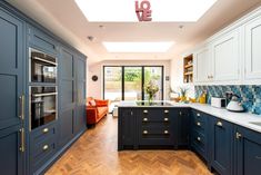 a kitchen with blue cabinets and white counter tops, wooden flooring and skylight