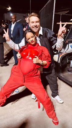 two people in red jumpsuits posing for the camera with one person holding a heart