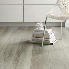 a white chair sitting next to a stack of books on top of a wooden floor