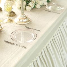 the table is set with silverware and flowers on it, along with other place settings