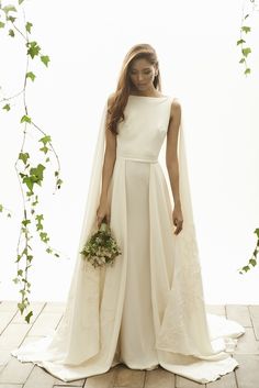 a woman in a white wedding dress with a veil on her head and flowers in her hand