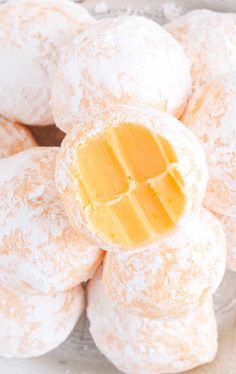 powdered sugar covered pastries on a plate with butter in the middle and one bite taken out