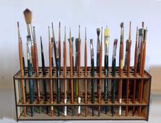 a wooden rack with lots of paint brushes on it's sides and two rows of them in the middle