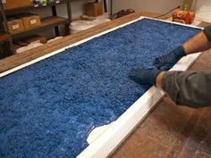 a man is working on an area rug in his garage with blue shag and white trim