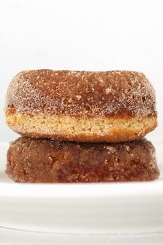 two donuts sitting on top of a white plate next to each other in front of a white background