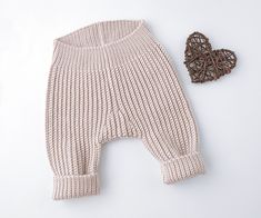 a knitted baby's outfit with a heart shaped object on the floor next to it