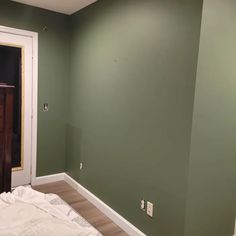 an empty room with green walls and white trim on the walls is being painted by someone