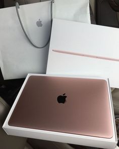 an apple laptop sitting on top of a table next to a white box and bag