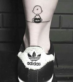 a person's foot with a small tattoo on the side of their leg and an adidas shoe