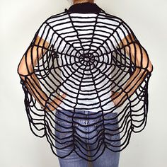 a person standing in front of a white wall with an umbrella shaped like a spider web