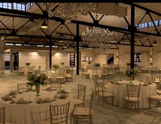 a large room with tables, chairs and chandeliers on the ceiling is set up for a formal function