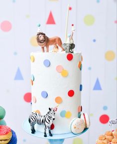 there is a cake decorated with animals and decorations on the top tier, along with other desserts