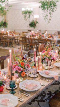 a table set up with plates, candles and flowers on it for a wedding reception