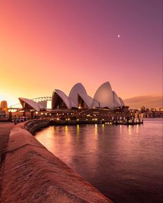 the sydney opera house is lit up at sunset