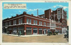 an old postcard shows the corner store and other buildings in this city street scene