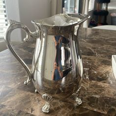 a silver pitcher sitting on top of a table