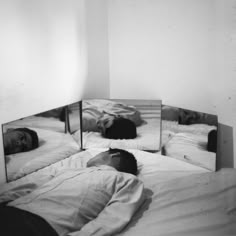 a person laying in bed with their head on the pillow and two mirrors reflecting them