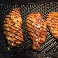 three pieces of meat cooking on a grill