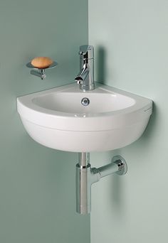 a white sink mounted to the side of a green wall next to a faucet