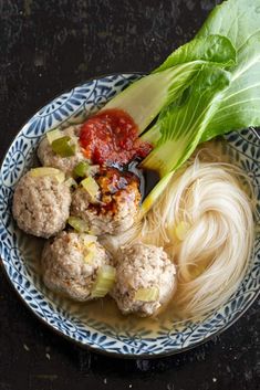 a bowl filled with meatballs and veggies on top of a black table