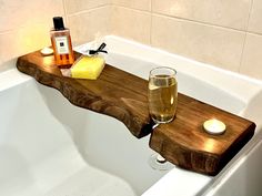 a bath tub with a wooden tray and two glasses on the edge next to it