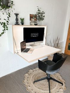 a desk with a laptop on it and a chair next to it in front of a plant