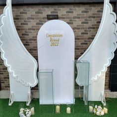 two large white angel wings sitting next to each other on top of a grass covered field