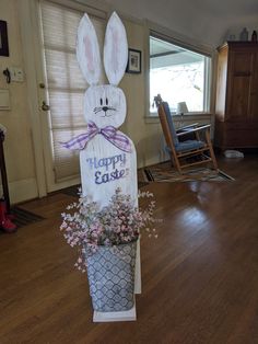 an easter decoration with flowers in a flower pot and a bunny sign on the door