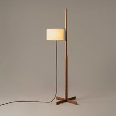 a floor lamp with a wooden base and a white fabric shade on the top light